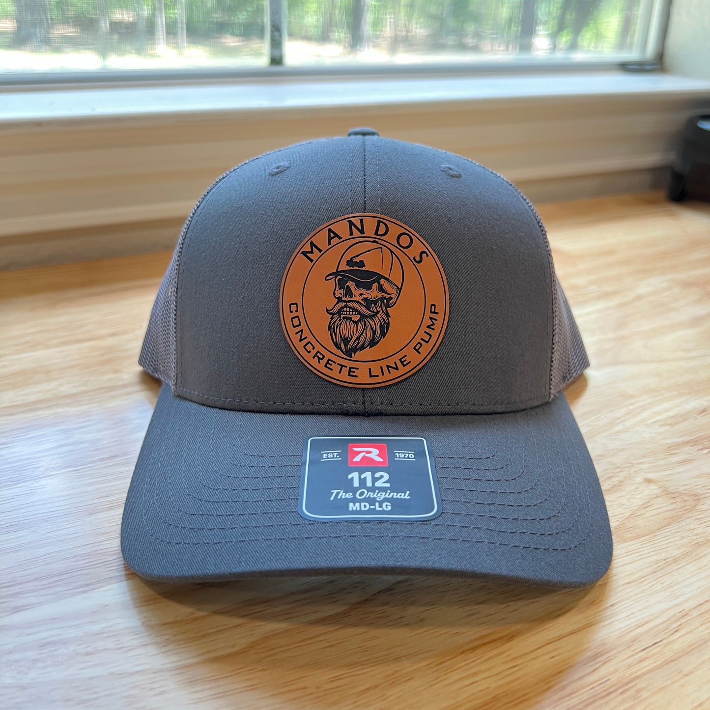 Gray cap with a logo on a wooden surface near a window