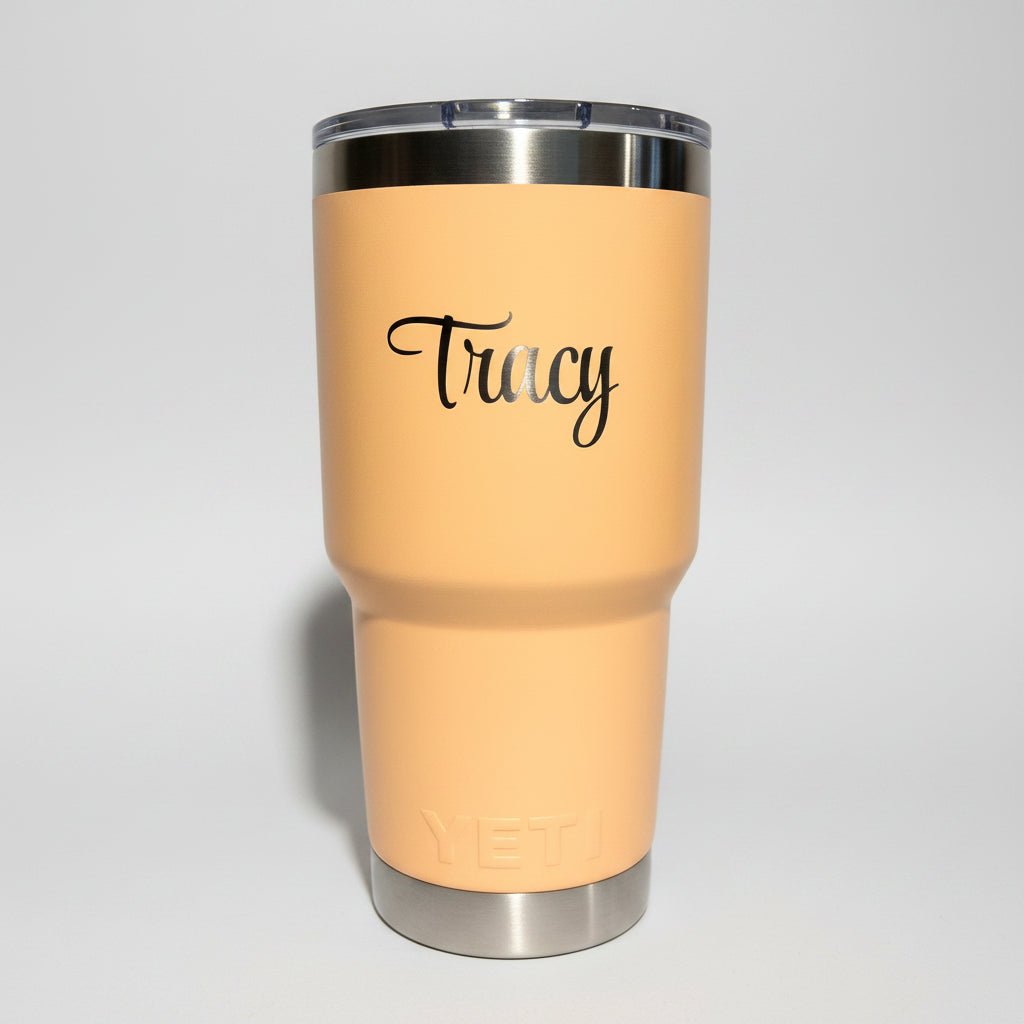 Beige tumbler with 'Fancy' text on a white stand against a gray wall.