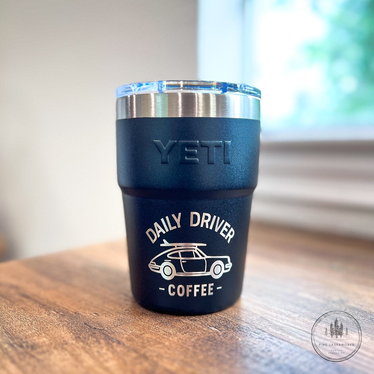 Black Yeti 16oz Rambler Stackable Tumbler with a laser engraved logo on a wooden surface.