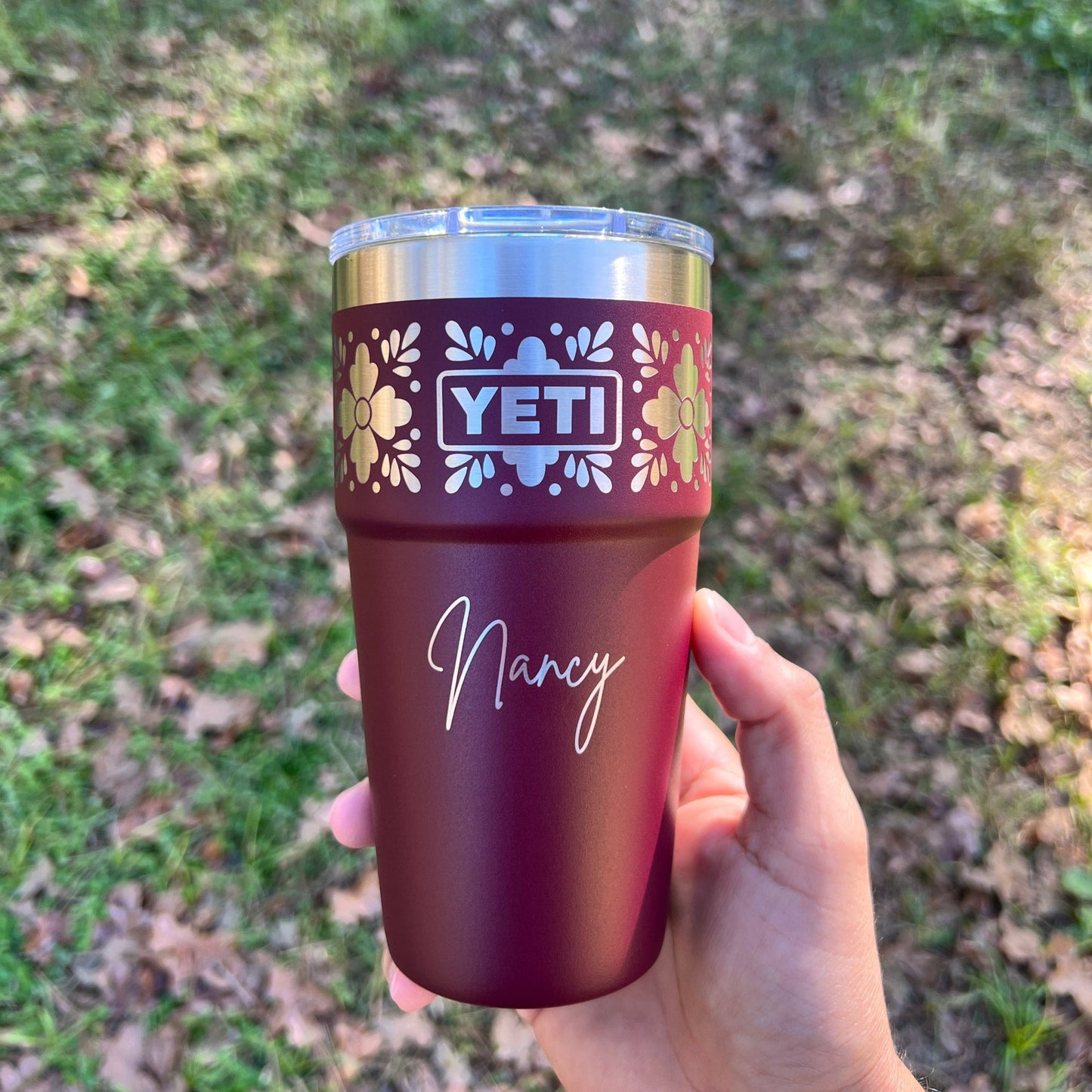 Personalized Talavera Flower Yeti 20oz Stackable Cup - Pine LaserworksHand holding a Wild Vine Red YETI tumbler with floral design and 'Nancy' text against a grassy background