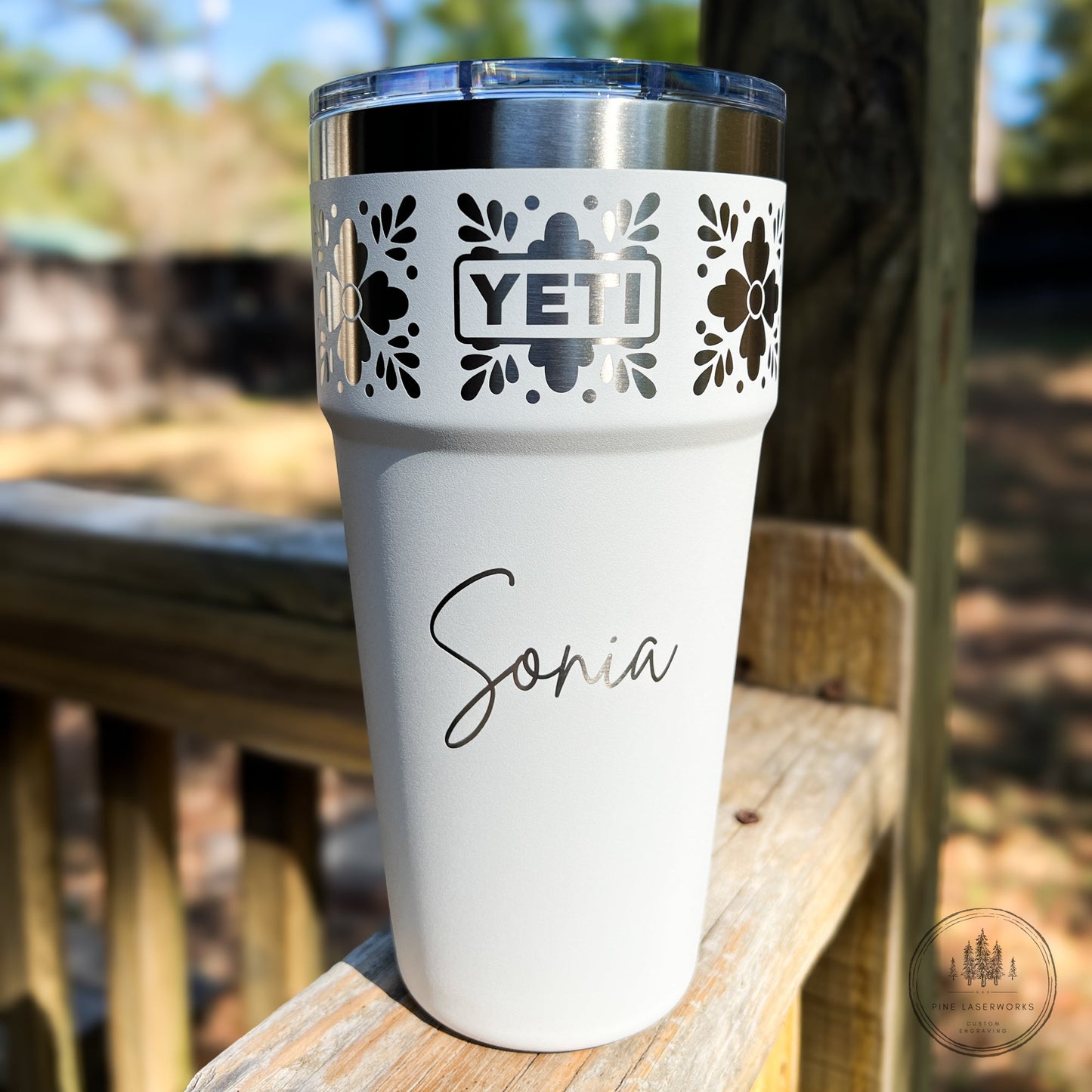 Personalized Talavera Flower Yeti 30oz Stackable Cup - Pine LaserworksWhite YETI tumbler with floral design and 'Sonia' engraving on a wooden surface outdoors.