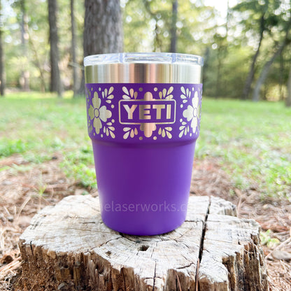 Pace Purple YETI mug with floral design on a wooden stump in a forest setting