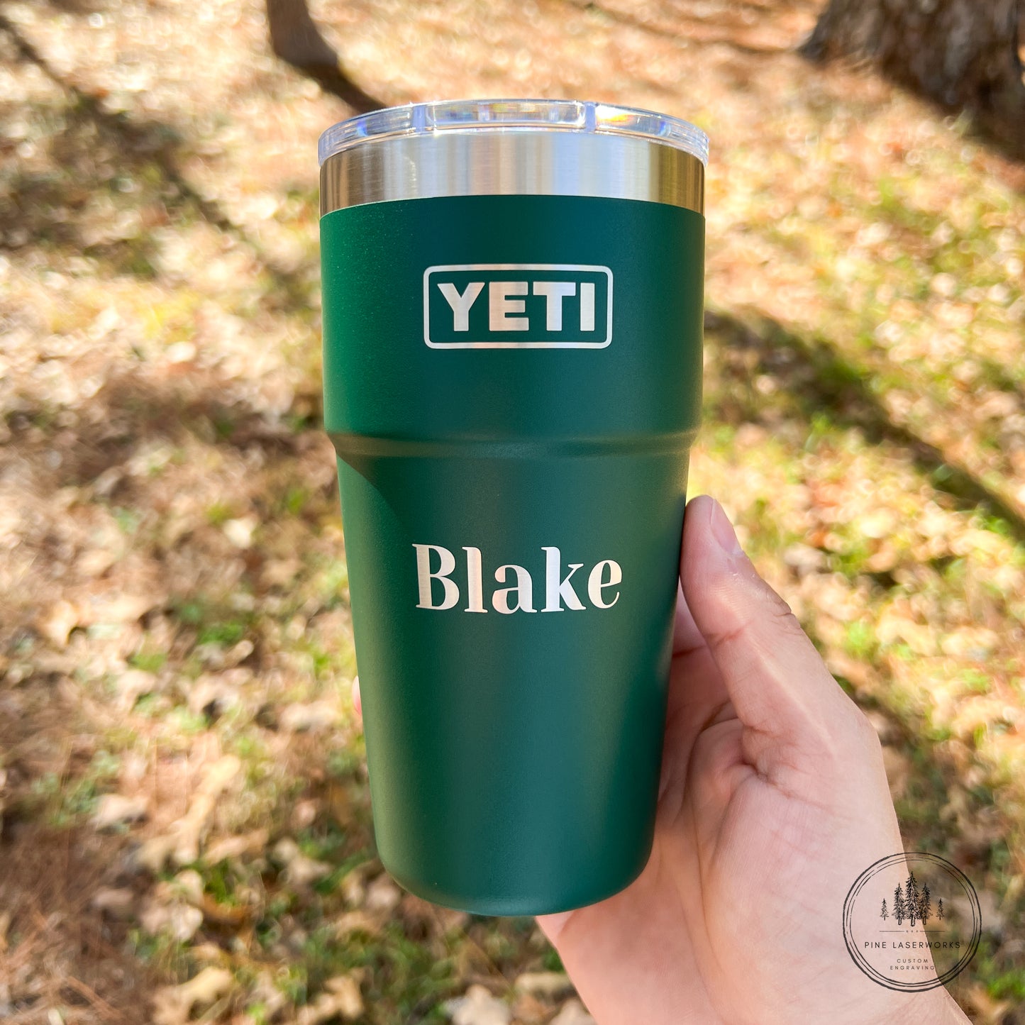 Black Forest Green YETI mug with 'Blake' personalized name held in a hand outdoors.