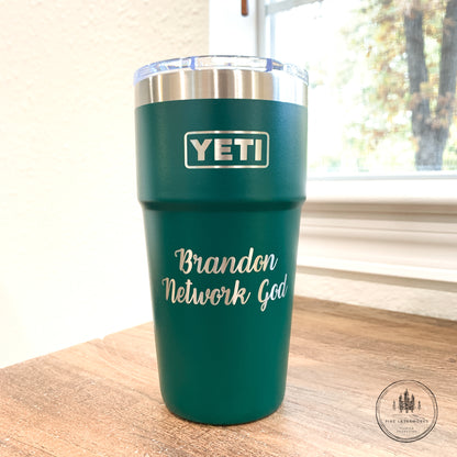 Black Forest Green YETI tumbler with 'Brandon Network God' text on a wooden surface.