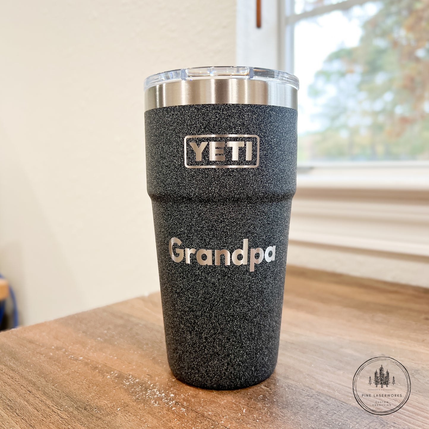 Black Grain YETI tumbler with 'Grandpa' engraving on a wooden surface.
