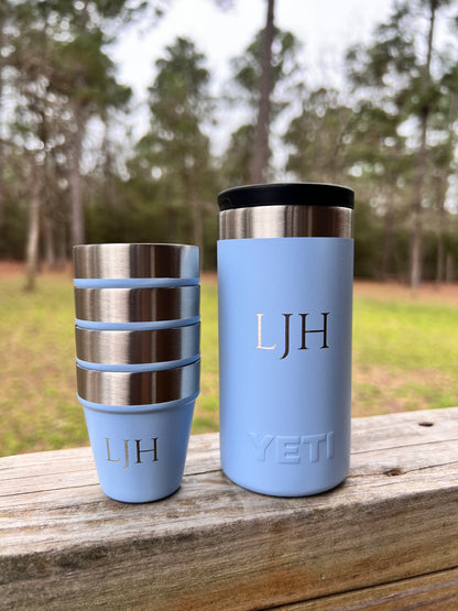 Two light blue YETI tumblers with monogram initials on a wooden surface outdoors.
