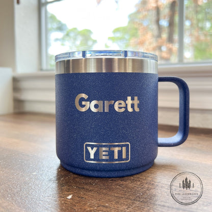 Blue YETI mug with 'Garett' branding on a wooden surface.