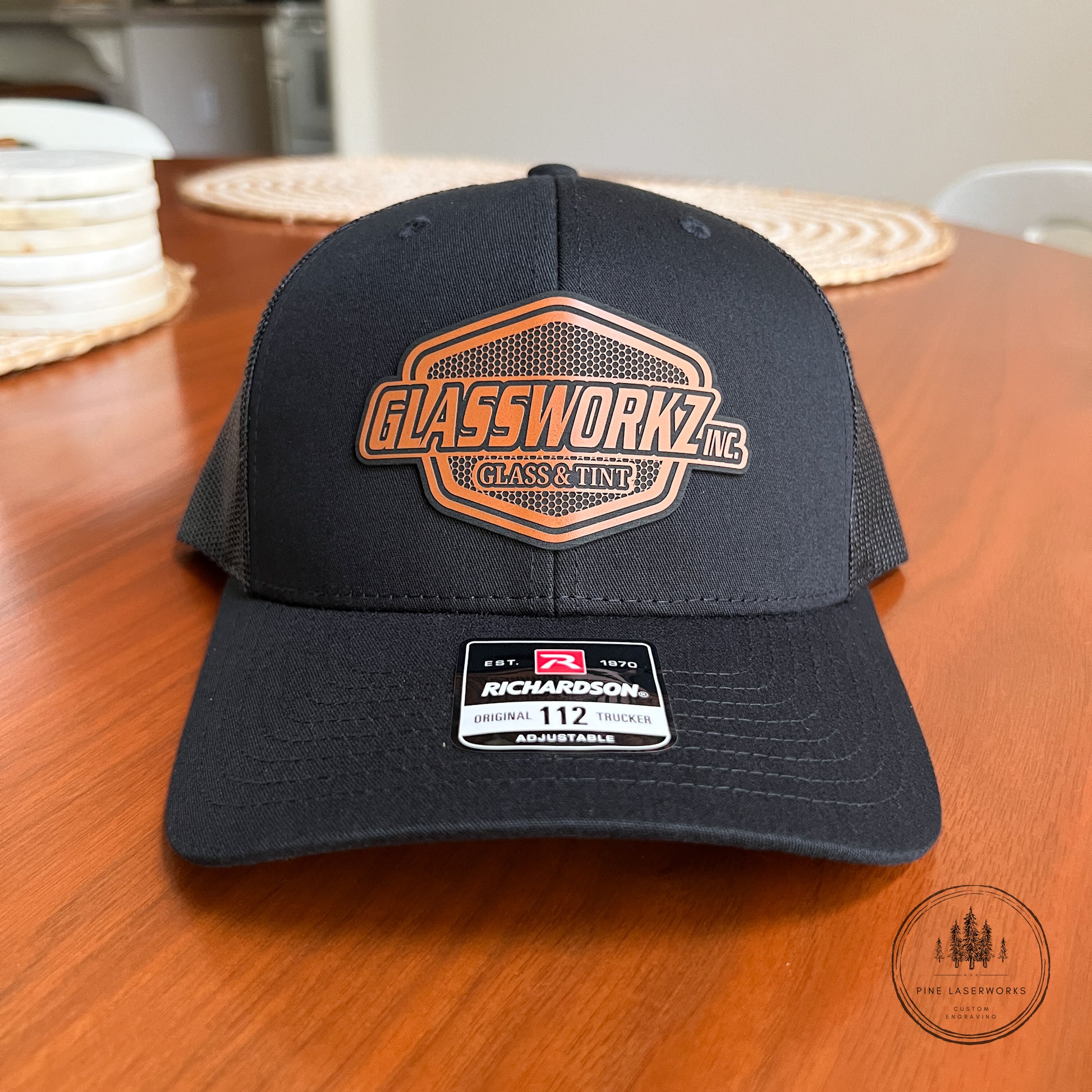Black cap with 'Glassworkz' logo on a wooden surface