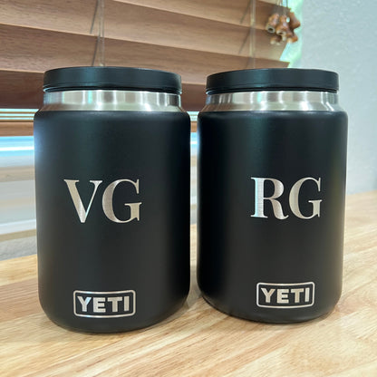 Two black YETI tumblers with initials 'RG' and 'VG' on a reflective surface.