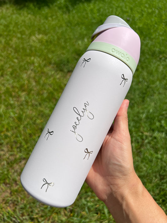 White water bottle with green accents held by a hand on grass