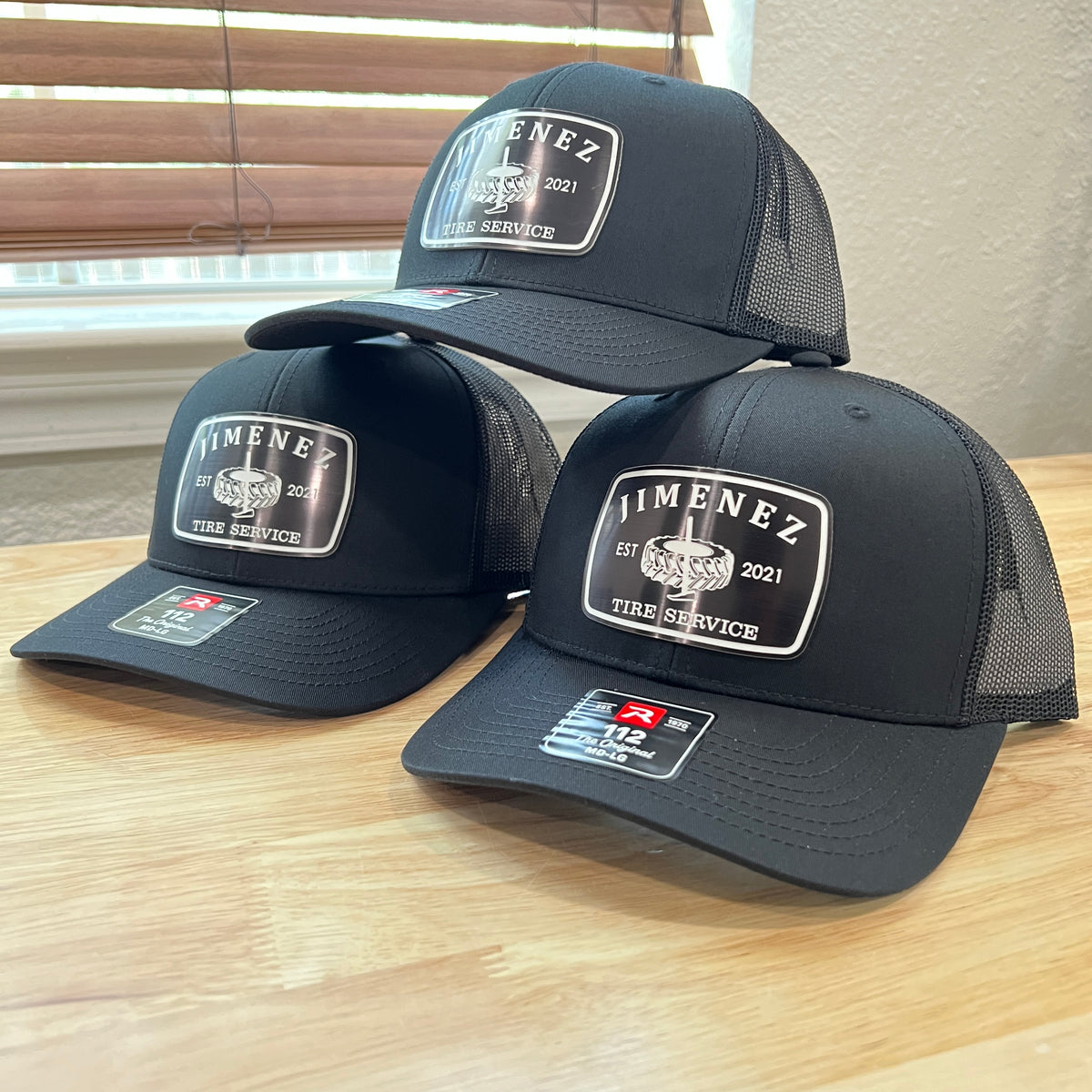 Three black Richardson 112 caps with white and black 'Jimenez Tire Service' acrylic patches