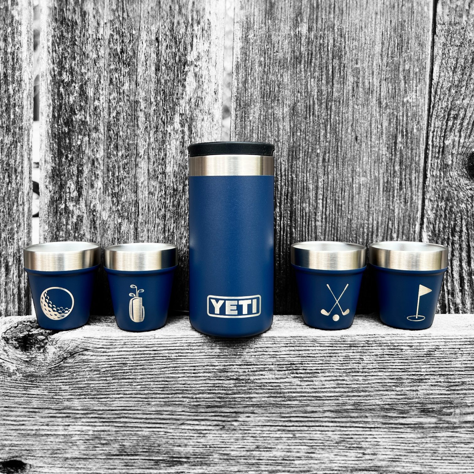 Set of blue YETI insulated cups with various designs on a wooden surface