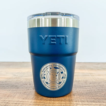 Navy Colored Yeti 16oz Rambler Stackable Tumbler with a round laser engraved logo on a wooden surface. 