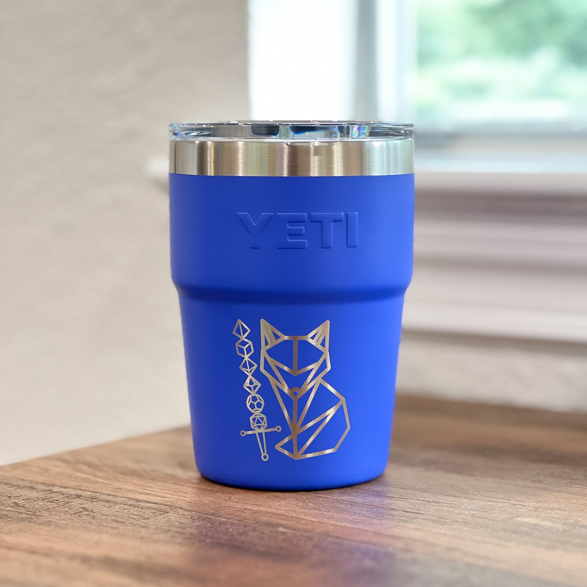 Ultramarine Violet Yeti 16oz Rambler Stackable Tumbler with a laser engraved logo on a wooden surface. 