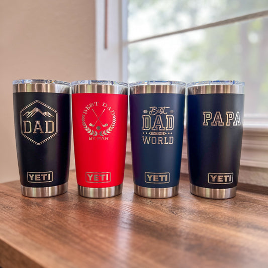 Personalized Dad Yeti 20oz Rambler Laser Engraved Tumbler - Pine LaserworksFour YETI tumblers with different designs and text on a wooden surface.