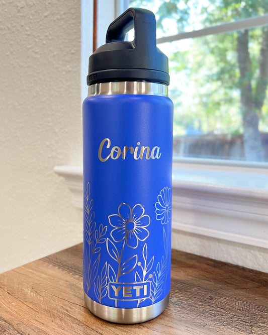Personalized Floral Yeti 26oz or 36oz Rambler Laser Engraved Water Bottle - Pine LaserworksUltraviolet Marine YETI water bottle with floral design and 'Corina' engraving on a wooden surface.