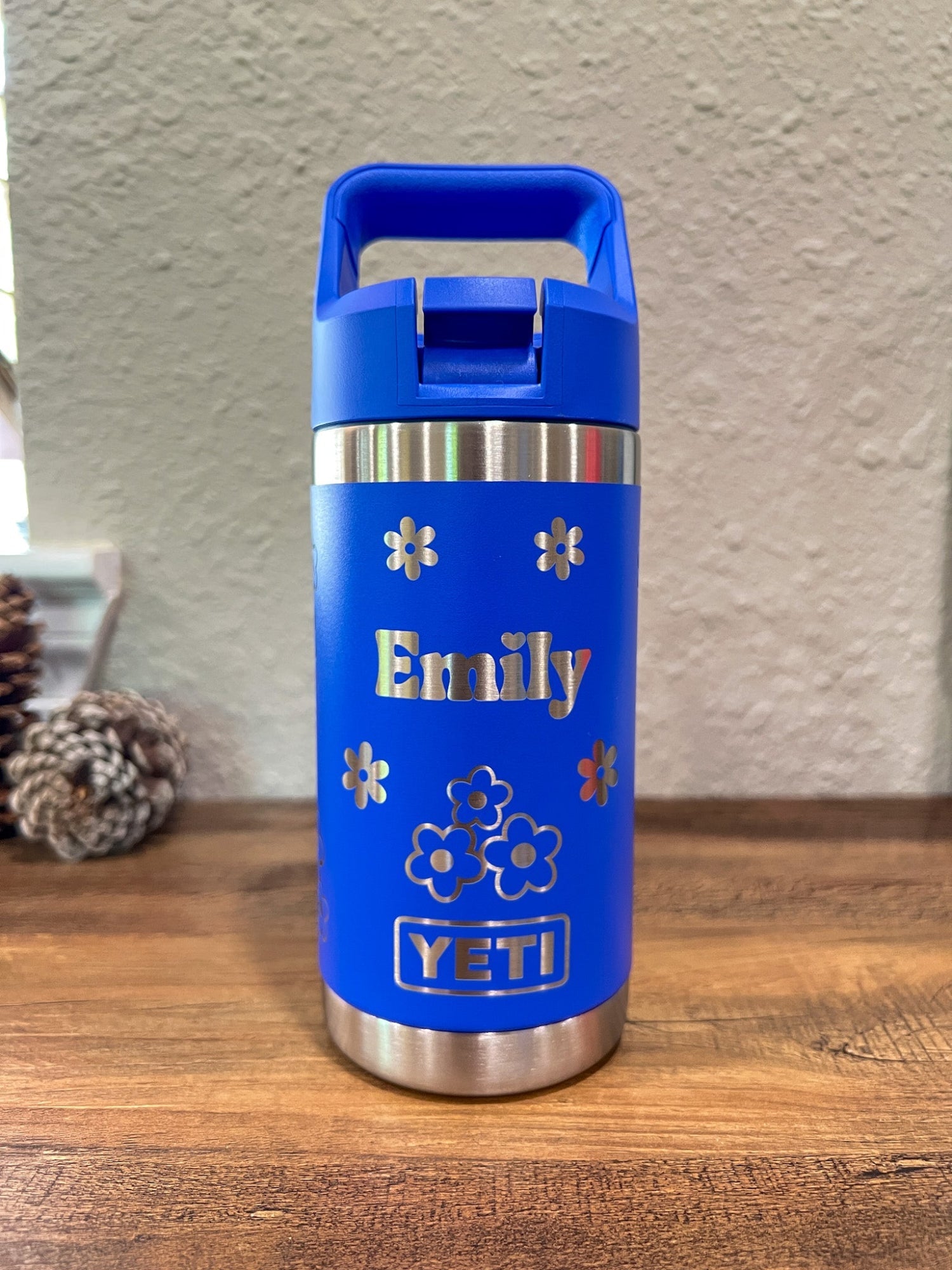 Personalized Kids Yeti 12 oz Water Bottle 12 Design Options - Pine LaserworksUltramarine Violet YETI water bottle with 'Emily' and floral designs on a wooden surface.