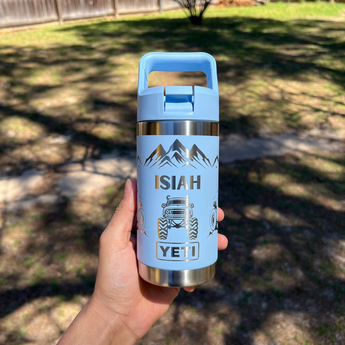 Personalized Kids Yeti 12 oz Water Bottle 12 Design Options - Pine LaserworksHand holding a YETI water bottle with a blue handle and 'YETI' branding outdoors.