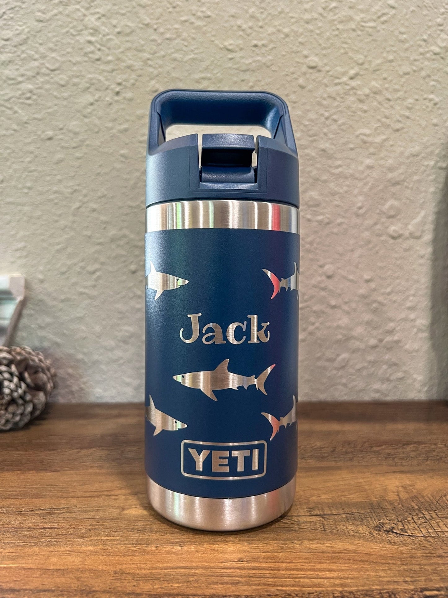 Personalized Kids Yeti 12 oz Water Bottle 12 Design Options - Pine LaserworksBlue YETI water bottle with shark design and 'Jack' engraving on a wooden surface.