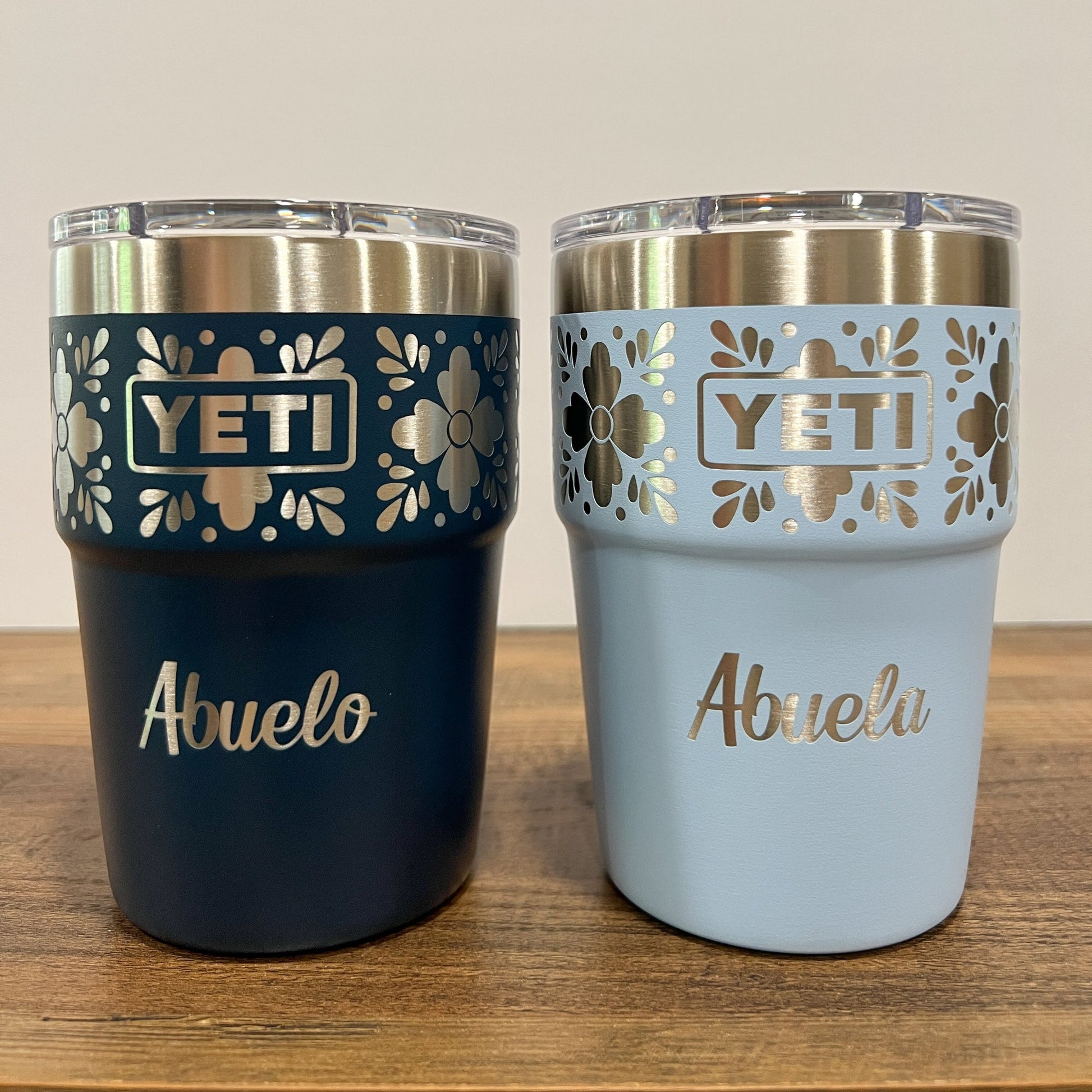 Personalized Talavera Flower Yeti 16oz Stackable Cup - Pine LaserworksTwo YETI tumblers, one navy and big sky blue, with 'Abuelo' and 'Abuela' text on a wooden surface.