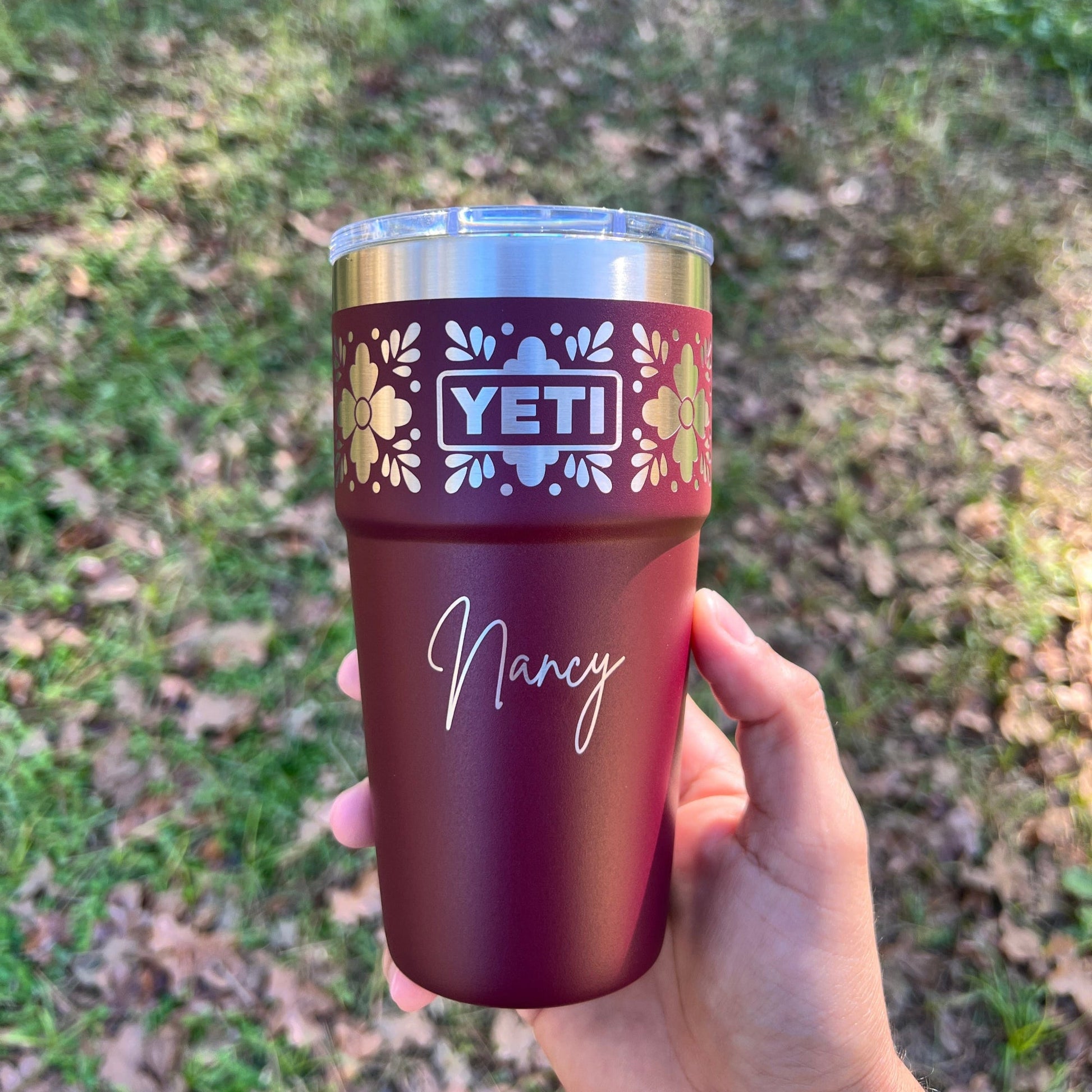 Personalized Talavera Flower Yeti 20oz Stackable Cup - Pine LaserworksHand holding a Wild Vine Red YETI tumbler with floral design and 'Nancy' text against a grassy background
