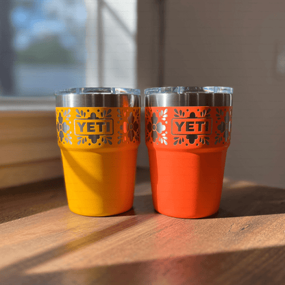 Talavera Flower Yeti 16oz Stackable Cup - Pine LaserworksBeekeeper and Papaya YETI tumblers on a wooden surface with a blurred window background.